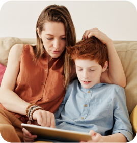 A mother teaching her son on tablet while sitting on the couch. A mother teaching her son on tablet while sitting on the couch.