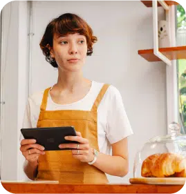 A standing woman in her kitchen ordering food from her tablet. A standing woman in her kitchen ordering food from her tablet.